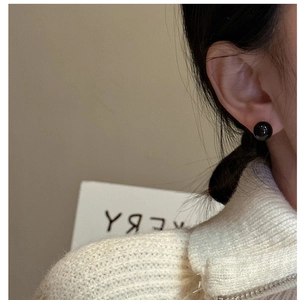 Close-up of minimalist black agate stud earrings on model for daily fashion look