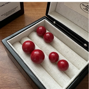 Macro view of red shell pearl studs in three sizes displayed in a wooden jewelry box