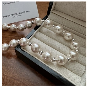 Macro detail of high-luster white pearls and silver beads in a black jewelry box
