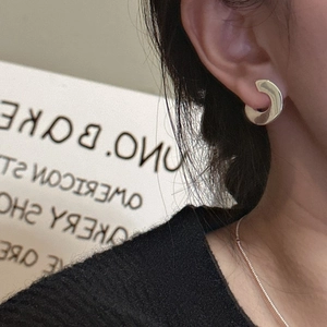 Polished gold S925 sterling silver C-shaped hoop earrings worn by a model in lifestyle setting
