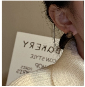 Detailed view of spherical tiger eye stud earring on model with vintage aesthetic