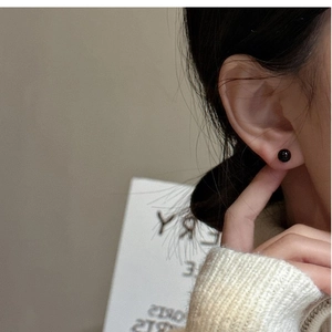 Close-up of minimalist black onyx stud earring on model with polished glossy finish