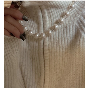 Detail of S925 sterling silver necklace with white pearls on a white knit sweater