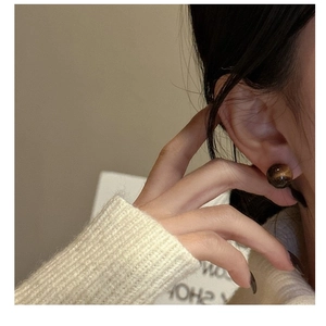 Detailed close-up of tiger eye stone stud earrings worn on the ear showing natural texture