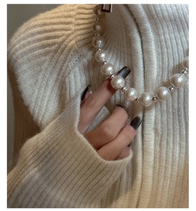 Close-up of S925 silver necklace with white pearls on a soft knit sweater