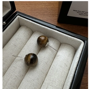 Macro detail of S925 silver stud earrings with polished brown tiger eye stone beads