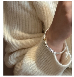 Gros plan d'un bracelet jonc S925 en argent bicolore avec une petite perle dorée chic
