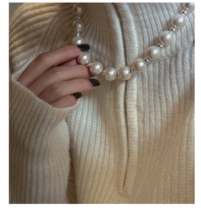 Detail of S925 sterling silver necklace with lustrous pearls on knit sweater