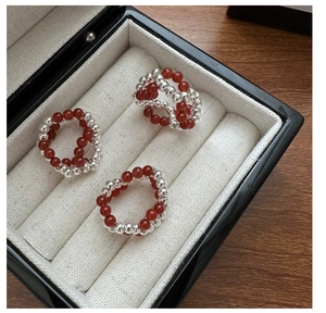 Close-up of three S925 silver beaded rings with red agate stones on fabric lining
