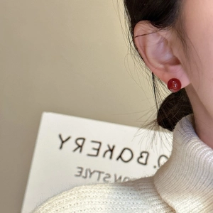 Elegant S925 sterling silver red agate stud earrings worn with a white sweater