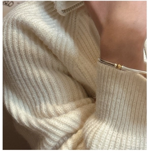 Détail du bracelet jonc en argent S925 avec perle dorée sur une manche en maille douillette
