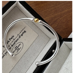 Gros plan détaillé du bracelet jonc en argent S925 bicolore avec perle dorée centrale