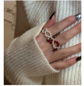 Detail of s925 silver beaded ring with red agate and pearls on a knit sweater background