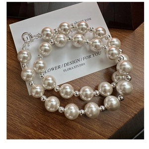 Detailed view of large white pearl necklace with silver accents and lobster clasp closure