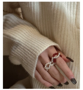 Detail of s925 silver beaded ring with red beads and pearls on hand with sweater
