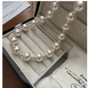 Detailed view of S925 silver pearl necklace with shiny white pearls in a jewelry box