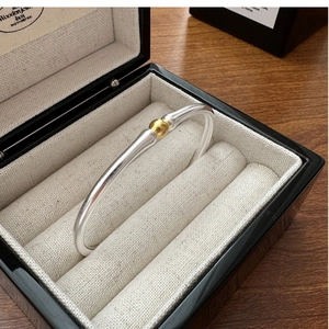 Détail du bracelet bicolore argent et or posé dans un coffret à bijoux de luxe