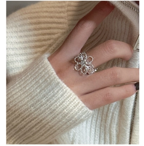 Close-up of S925 silver hollow flower ring with zircon on a knit sweater background