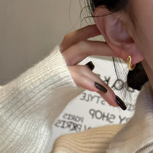 Boucles d'oreilles créoles dorées en argent S925 en forme de C portées par un modèle