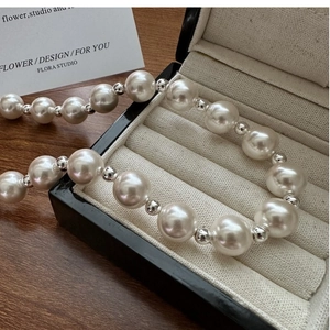 Detail of high-luster white pearl necklace with silver beads on velvet jewelry display