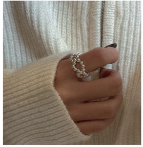 Detail of s925 silver double-loop pearl ring worn on hand with white knit background