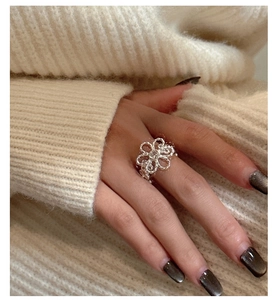 Close-up of S925 silver flower ring with zircon on a hand wearing a knit sweater