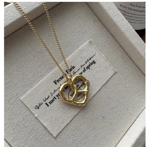 Détail du pendentif cœur doré à texture martelée sur une fine chaîne en maille jante