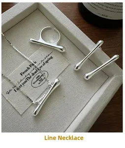Macro shot of S925 sterling silver minimalist streamline necklace, ring, and earring set