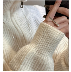 Close-up of a minimalist silver liquid stream ring worn against a white sweater background