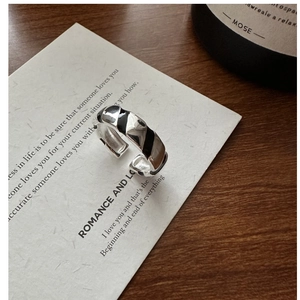 Detail of S925 silver diagonal twisted ring with black enamel on minimalist background