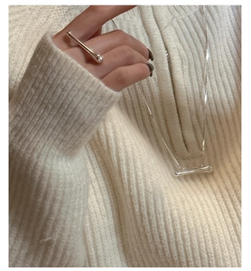 Close-up of fluid silver ring and pendant on minimalist knitwear background