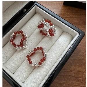 Macro detail of three beaded silver rings with red carnelian beads on white jewelry display