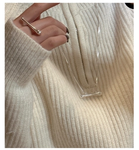 Detail of S925 sterling silver liquid metal necklace on white knit sweater