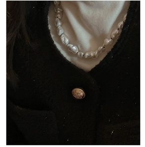 Detail of baroque irregular pearl necklace with natural white luster on a model