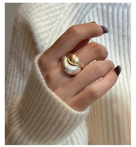 Macro detail of mixed gold and silver minimalist wavy rings worn on hand