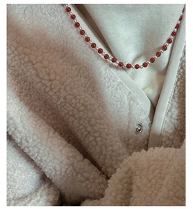 Detail of S925 silver necklace with red agate and pearls on a white fleece jacket