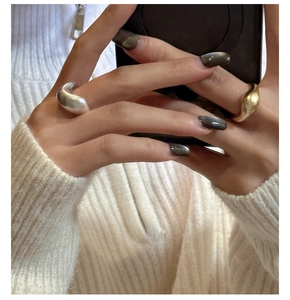 Detailed view of irregular wavy liquid metal rings in polished gold and silver finishes