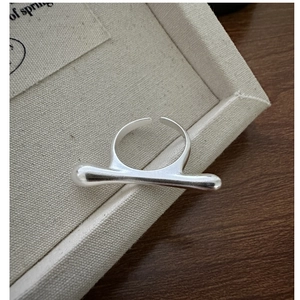 Macro shot of minimalist S925 sterling silver ring with liquid streamline cylinder detail