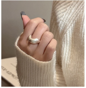 Macro shot of minimalist thick irregular U-shaped silver ring on a white knitted sweater