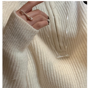 Detailed view of silver liquid-style necklace and long bar ring on knit fabric
