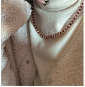 Detail of vintage beaded necklace with red agate and small pearls on model