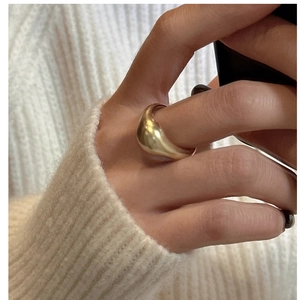Close-up of minimalist wide gold-plated ring on hand with white knit sweater background