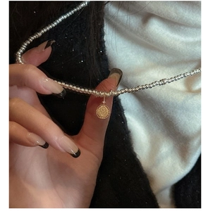 Detail of S925 silver beaded chain with a vintage gold coin pendant and zircon inlay