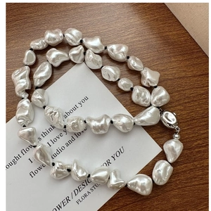 Close-up of irregular Baroque pearls with silver clasp and black rope necklace