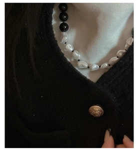 Detail of s925 silver necklace with black onyx beads and baroque pearls on a tweed coat