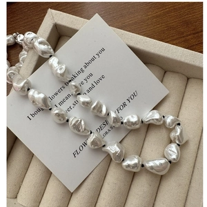 Close-up of baroque irregular pearl necklace with black cord on velvet tray