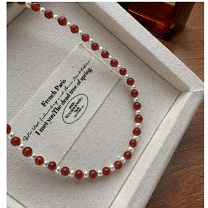 Detailed view of S925 silver necklace with red agate beads and pearls on a jewelry tray