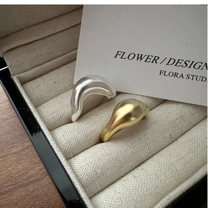 Detailed close-up of matte gold and silver organic wave rings in a black jewelry box