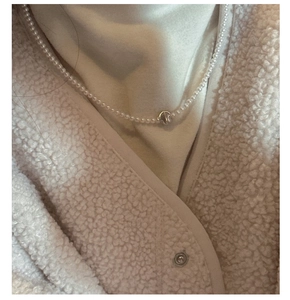 Macro view of dainty S925 silver beaded necklace with cat eye stone on a model wearing wool