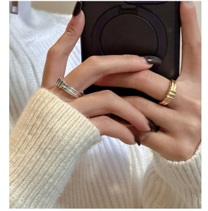 Detailed view of silver and gold wide rings with vertical texture on hand with sweater